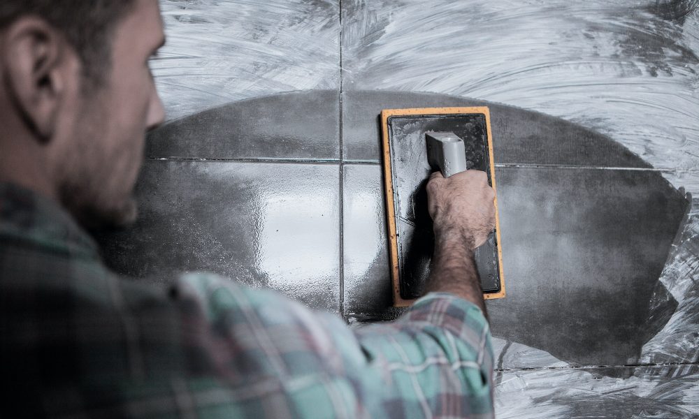 A mason cleans stained tiles with a sponge.