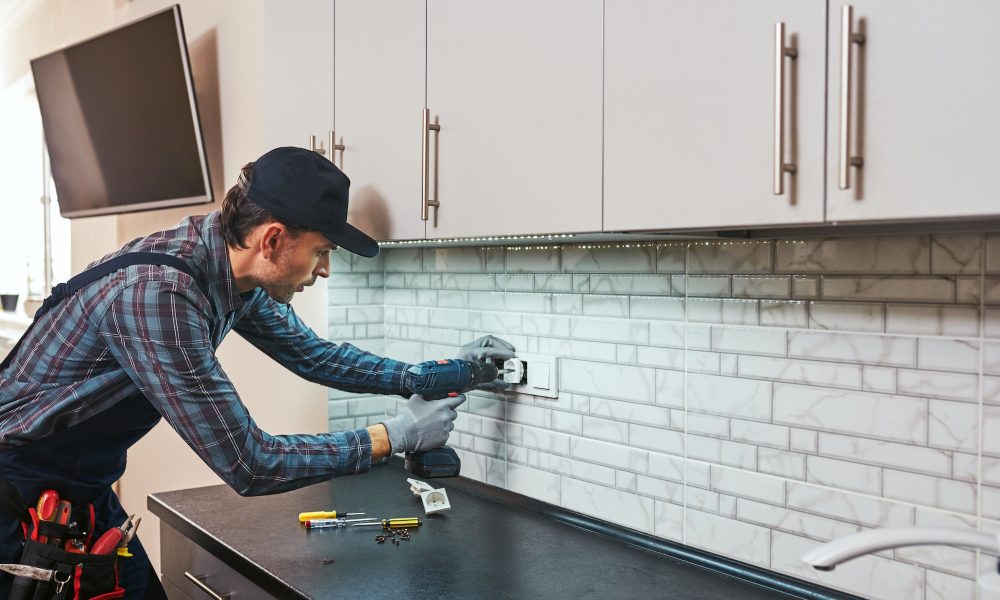 Electricity protection. Side view of young handyman with perforator